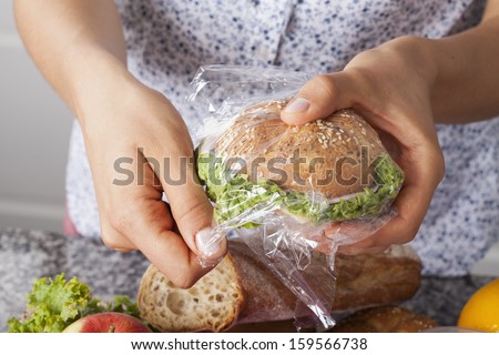 Mother foiling a sandwich for her child for a school meal
