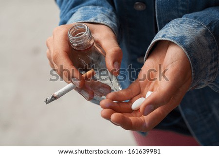 Young woman smoking cigarettes, drinking vodka and taking pills