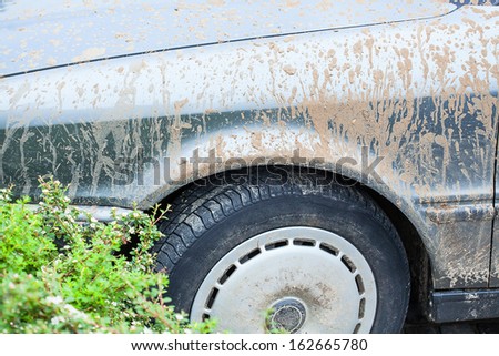A closeup of a dirty wheel and car\'s body
