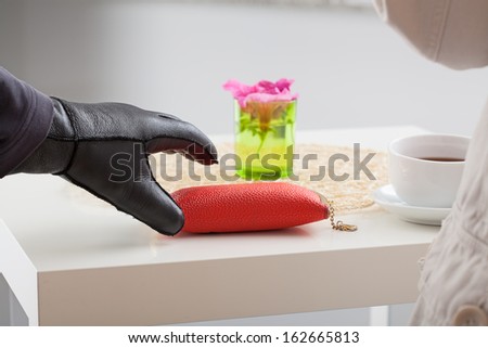 A closeup of a hand with a glove trying to steal a glasses case