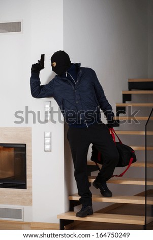 Burglar with a gun running away with loot