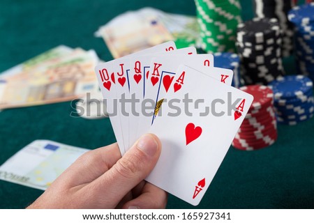 Man\'s hand holding royal flush in poker game