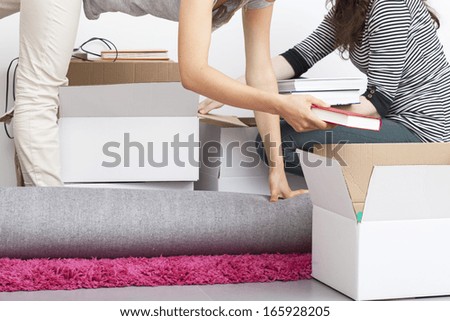 A woman packing things into a box in a tricky pose