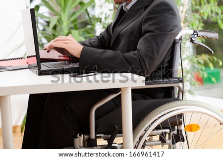 A disabled businessman on a wheelchair working on a laptop
