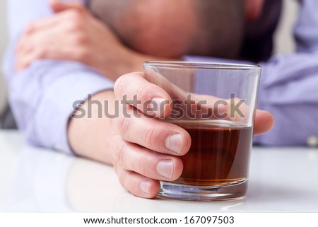 A closeup of a depressed alcoholic holding a glass of whiskey