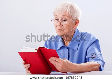A grandma in glassed reading a red book
