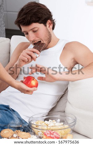 Boy sitting on couch prefers chocolate than apple