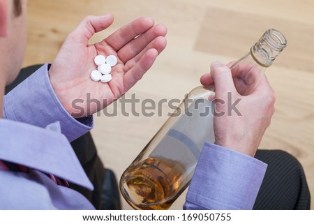 Drunk man wearing suite taking a drugs and drinking an alcohol