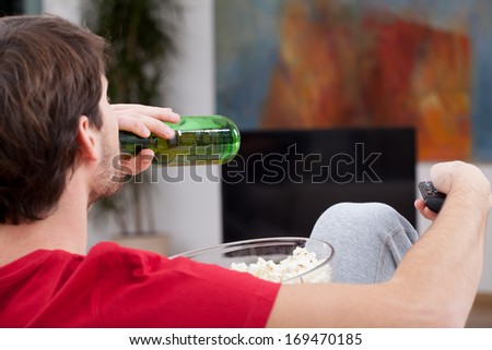 Match time, man sitting on a couch with beer and popcorn