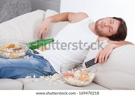 Full and drunk man lying on a couch
