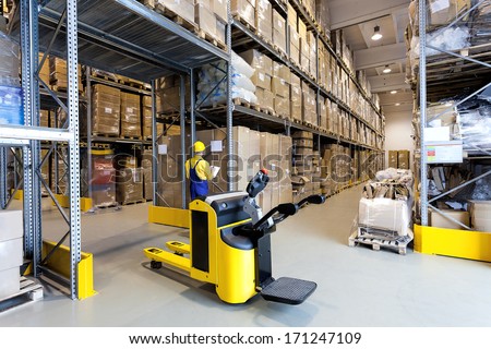 Huge metal stillage and yellow hand pallet truck in warehouse