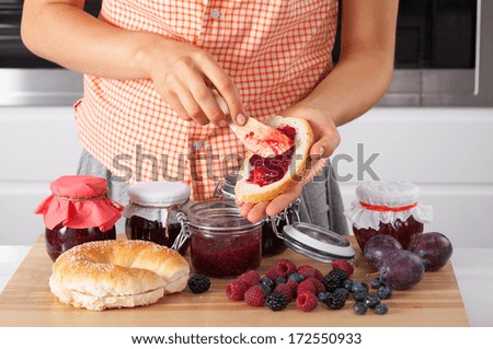 Woman spreading the bread with homemade jam from wildberries