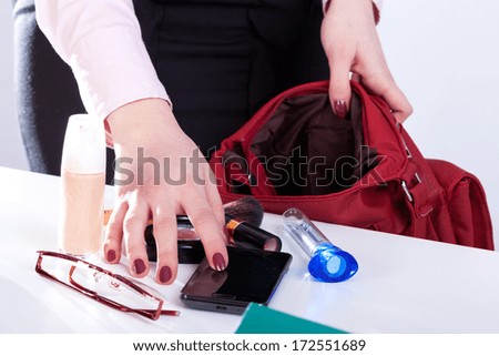Woman packing personal stuff to her handbag