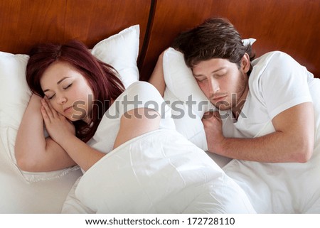 Couple sleeping peacefully under the  white duvet