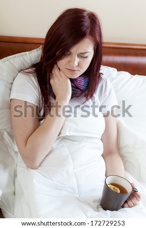 Woman with throat infection holding a mug with tea