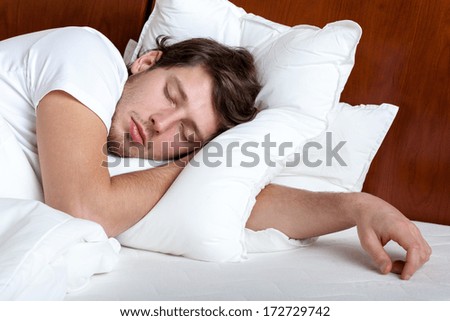 Yong man sleeping in his bed on white pillow