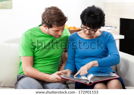 Elderly mother showing the family pictures to her adult son