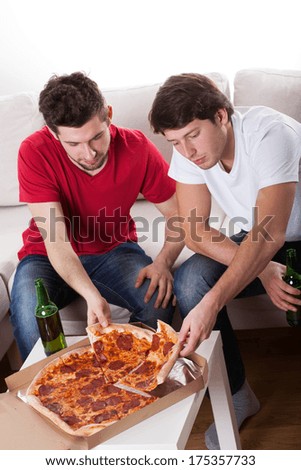 Two men friends eating pizza and drinking beer