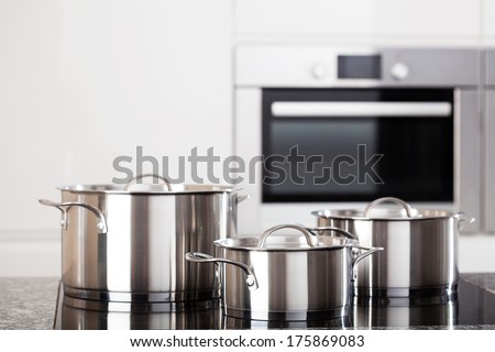 Three new metal pots in the kitchen on induction hob on modern kitchen background