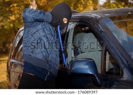 A masked thief striving to steal a big car