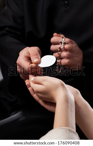 Catholic priest giving beliver a Holy Communion