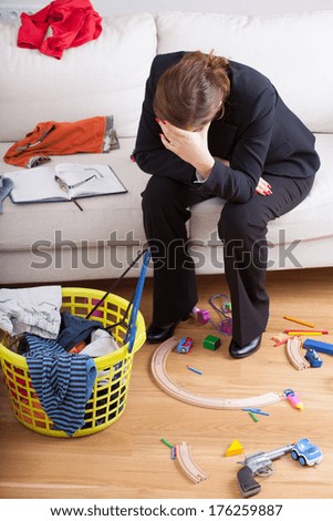 An elegant woman crying over dirty laundry and kids\' toys