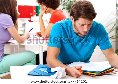 A male student reading his notes while studying at university
