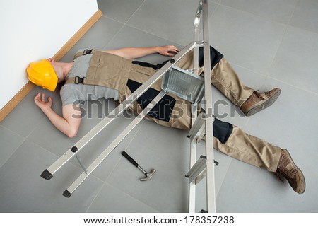A worker pinched by a ladder which has fallen on him