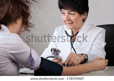 Elder female doctor measuring blood pressure of patient