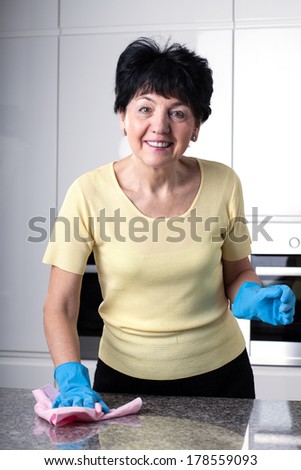 Elder woman is cleaning kitchen after cooking