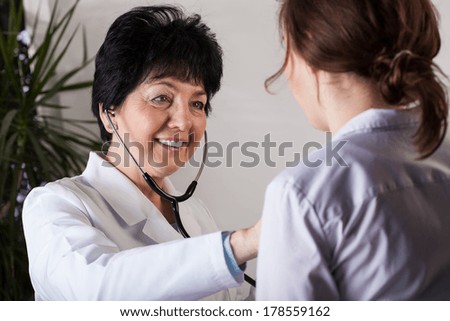 Elder female doctor examines young patient