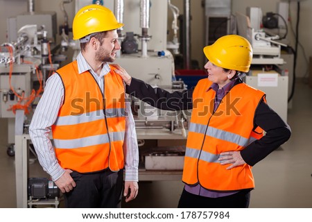 Smiling employees discussing at production area,horizontal