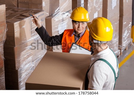 Manager giving worker instruction about loads storage in warehouse