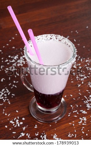 Layered drink in glass with handle and straws