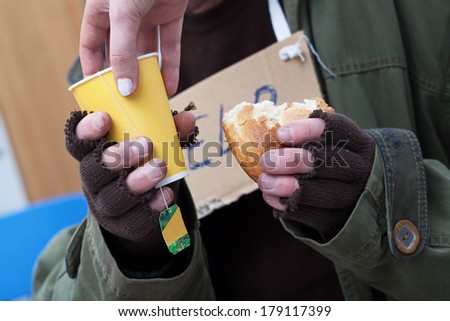 Women giving hot tea to poor homeless man