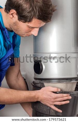 Handyman in blue overalls emptying vacuum cleaner