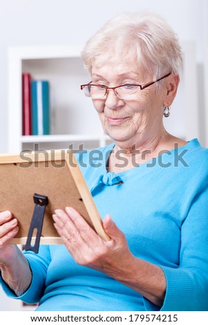Elderly lady wearing glasses viewing family picture