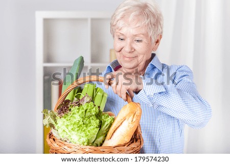 Elderly woman with shopping basket at home