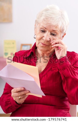 Old woman reading letter from her granddaughter and crying