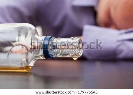 Drunk man sleeping with almost empty bottle of alcohol