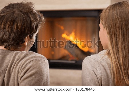 A man and a woman sitting by a fireplace