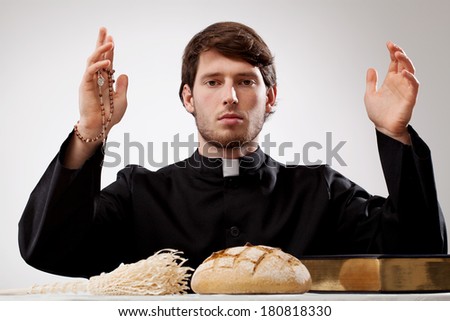 Young priest with rosary bread sprinkler and Holy Bible
