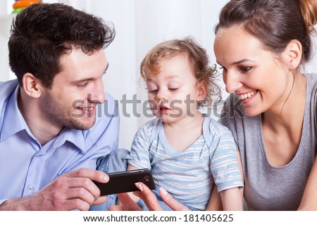 Parents with son viewing photos on mobile phone