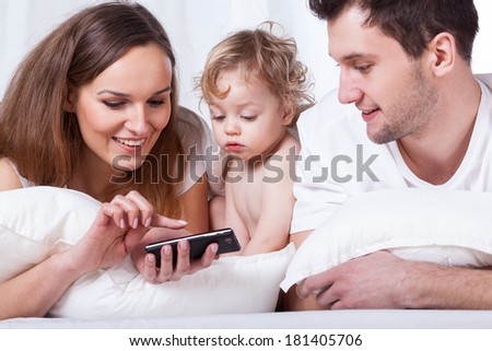 Parents and child watching photos on cellular phone