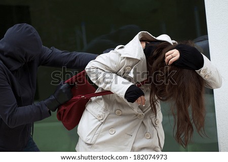 A masked thief attacking an innocent woman in the street
