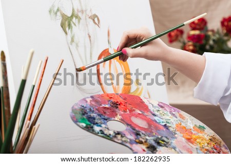 A closeup of an artist with a brush painting a picture