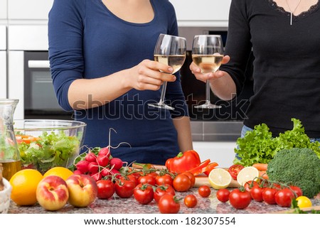 Lesbian couple preparing dinner and drinking wine at home