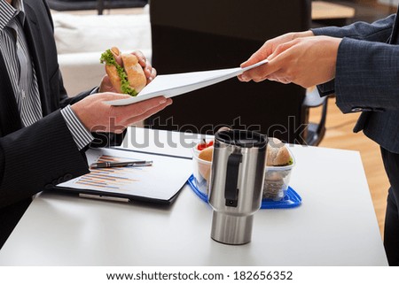 Worker eating lunch in office and getting a task