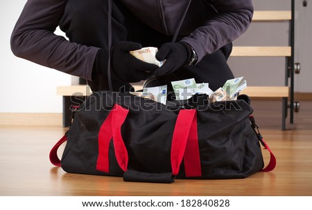 Burglar wearing gloves counting the stolen money