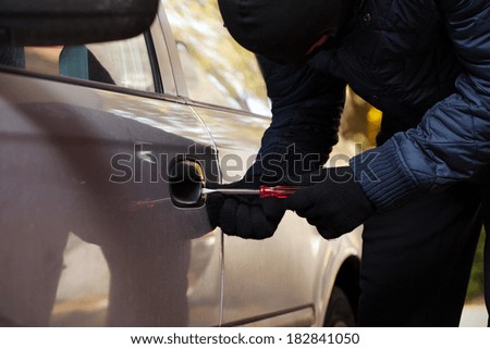 A burglar opening car\'s door by breaking in